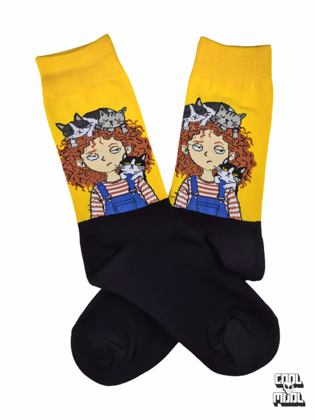 Cute curly-haired girl wearing dungarees with sleeping cats on her head woven crew socks made of bright yellow and black cotton fabric.